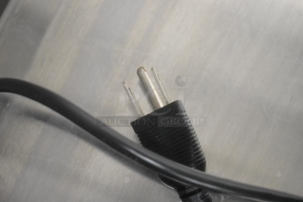 Close-up of a black power plug for a Samsung P2450 monitor, showing prongs and part of the cord.