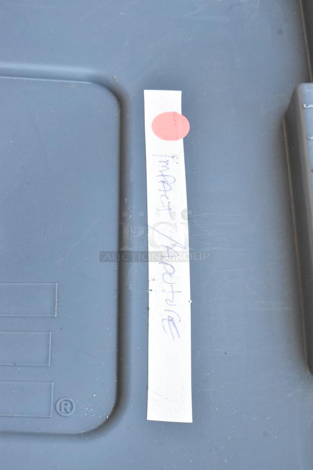 Poly bin labeled "Impact Aputure," part of an auction lot of various items. Grey surface with a red sticker.