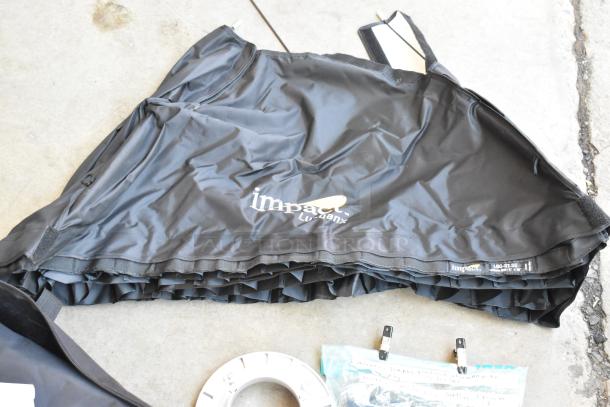 Poly bin containing various items, including an Impact softbox with logo, and a labeled Aputure accessory bag. Items appear in good condition.