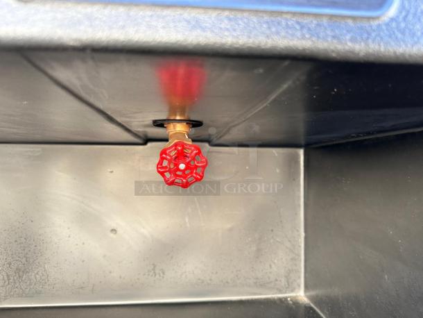 Red valve handle inside black Cambro BAR540DS portable bar, indicating plumbing feature.