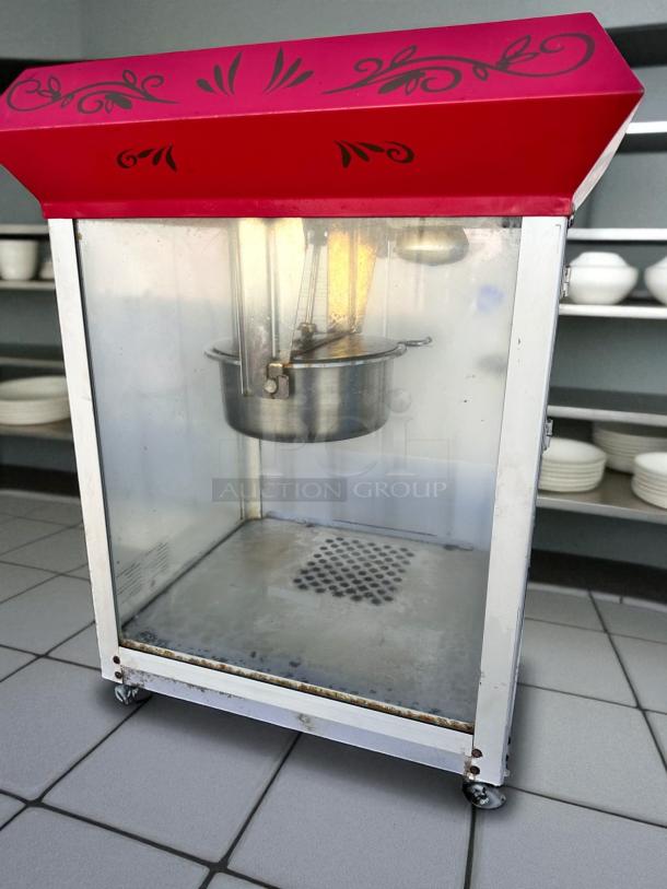 Vintage-style commercial popcorn machine in excellent condition, red top with black designs, fully tested and working.