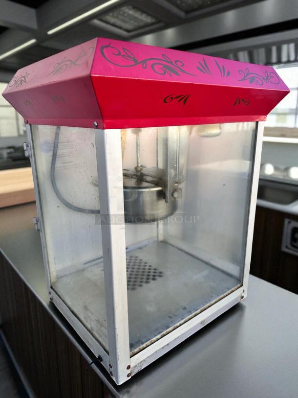 Vintage-style commercial popcorn machine in excellent condition, fully tested and working, red top with decorative patterns.