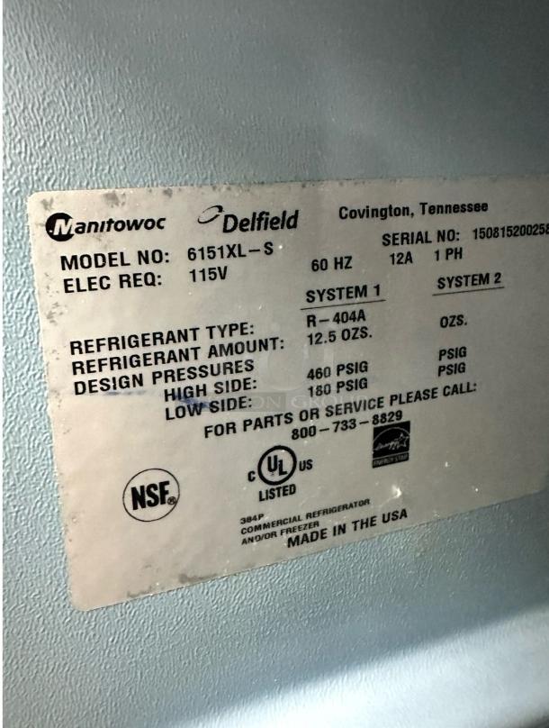 Label on Delfield 6151XL-S freezer showing model, electrical requirements, refrigerant type, and pressures. Made in USA.