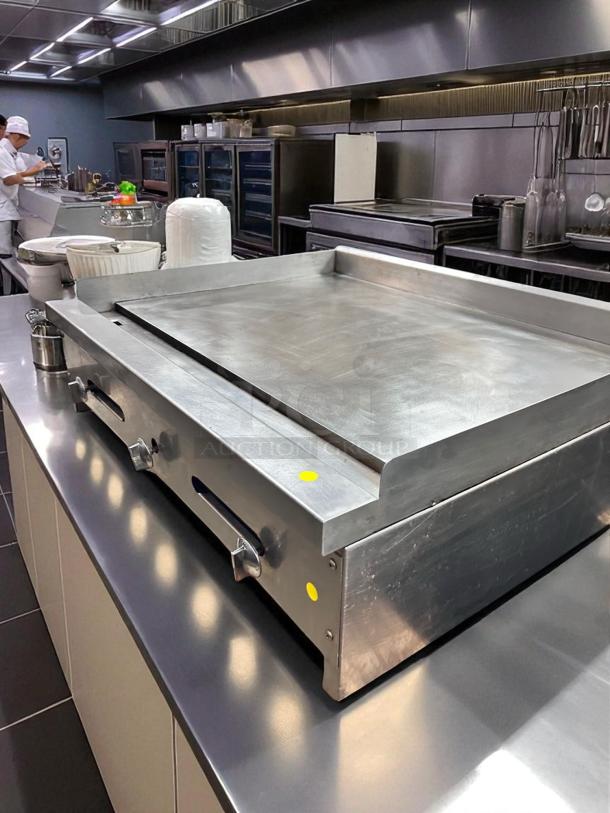 36" commercial flat top griddle in outstanding working condition, stainless steel, tested, with control knobs and markings.