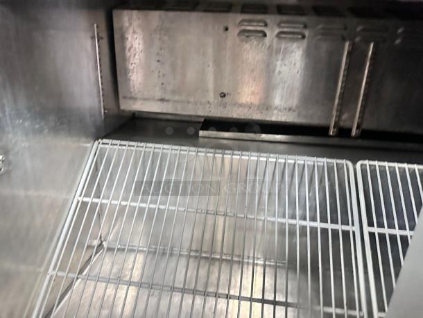 Continental 3-door stainless steel refrigerated prep table interior, excellent condition, with wire shelves, fully tested.