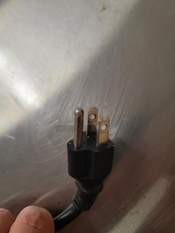 Close-up of Avantco refrigeration stainless steel surface with a three-pronged power plug.