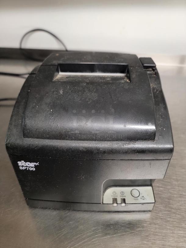 Star SP700 printer on a stainless steel work table. Printer shows minor wear; ideal for kitchen or workspace efficiency.