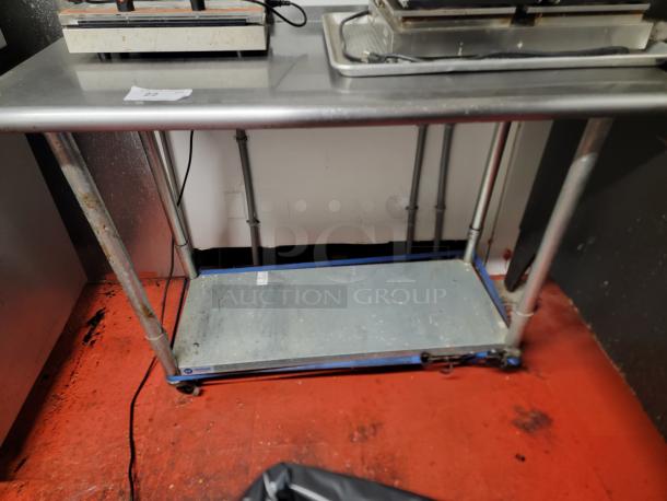 Gridman NSF Certified 4-Foot Stainless Steel Work Table with casters, showing slight wear, ideal for commercial kitchens.