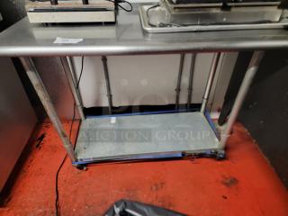 Gridman NSF Certified 4-Foot Stainless Steel Work Table with casters, showing slight wear, ideal for commercial kitchens.