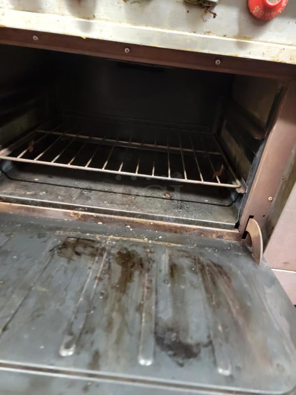 Vulcan 4-burner commercial range detail, showing oven interior with wire rack. Unit needs cleaning.