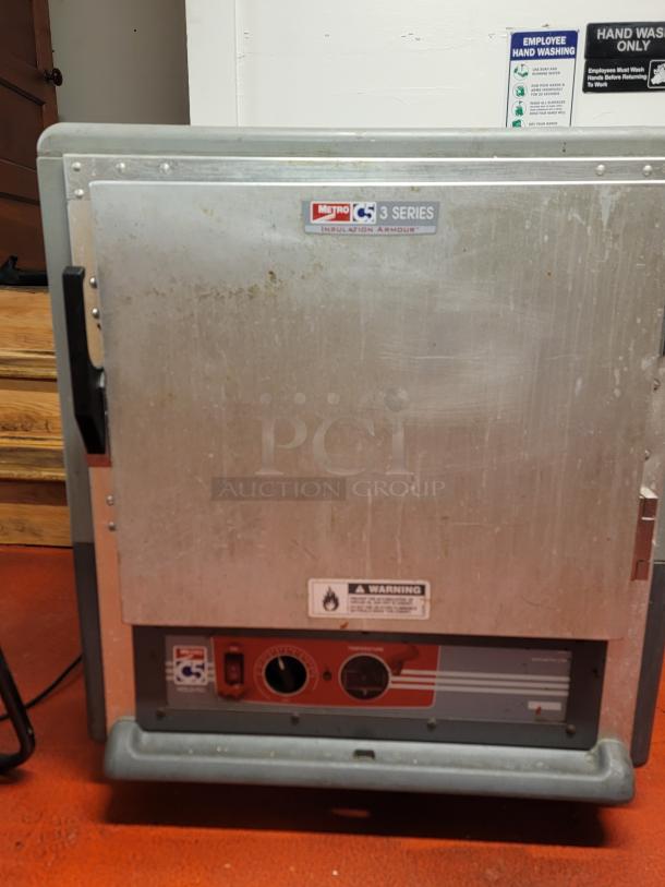 Metro C5 3 Series heated holding cabinet on casters, model C533-HLFS-U-GY, shows signs of use; ideal for food quality preservation.