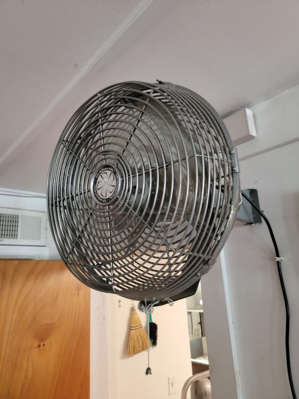 Industrial wall-mounted fan, metal grille, in good condition; ideal for commercial spaces needing robust air circulation.