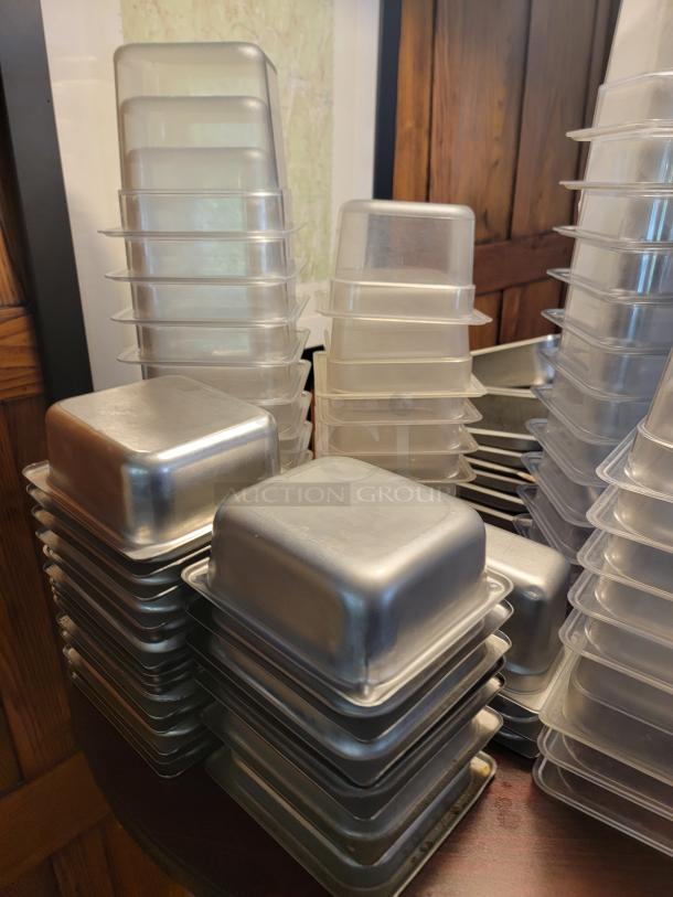 Assorted commercial food containers in plastic and stainless steel, stacked neatly. Ideal for food storage, durable condition.