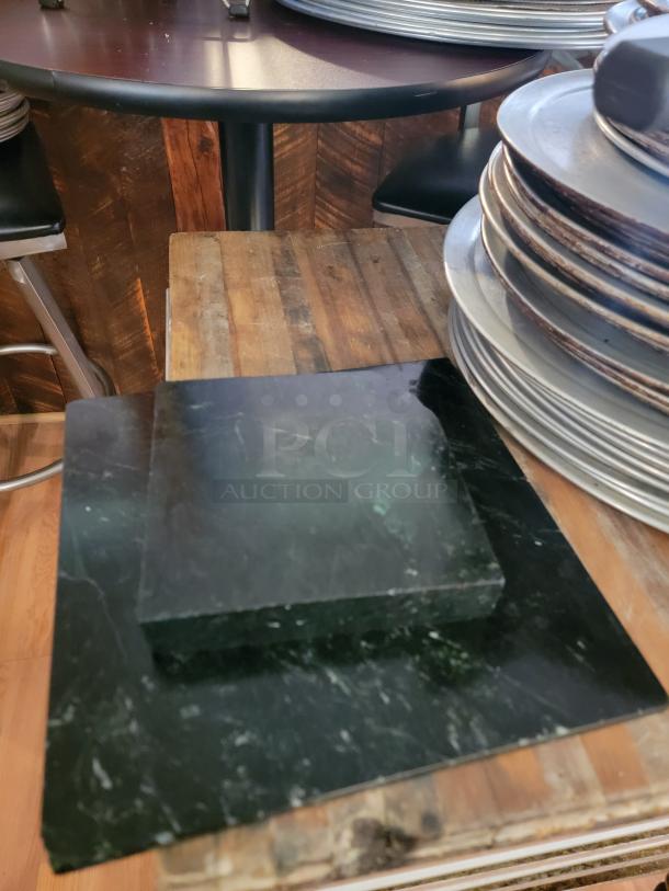 Stacks of commercial pizza pans on wooden table; includes marble cutting boards. Ideal for pizzerias or food trucks.