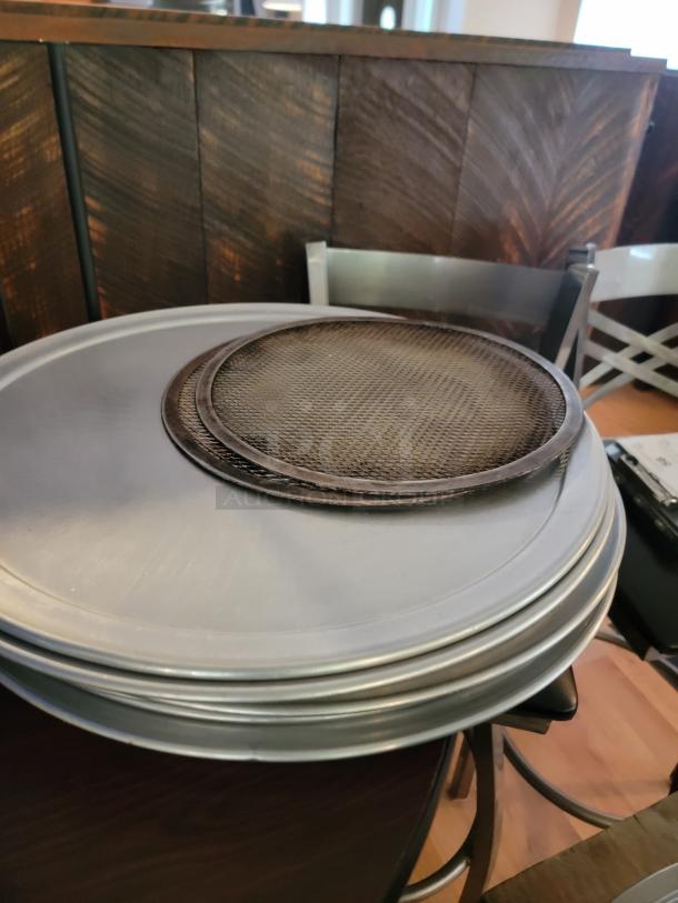Stack of perforated and solid pizza pans, and a pizza screen. Ideal for commercial or home use.