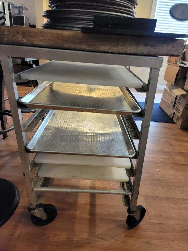 Commercial pizza rack with perforated pans, cutting boards, and trays on rolling cart. Ideal for pizzerias or food trucks.