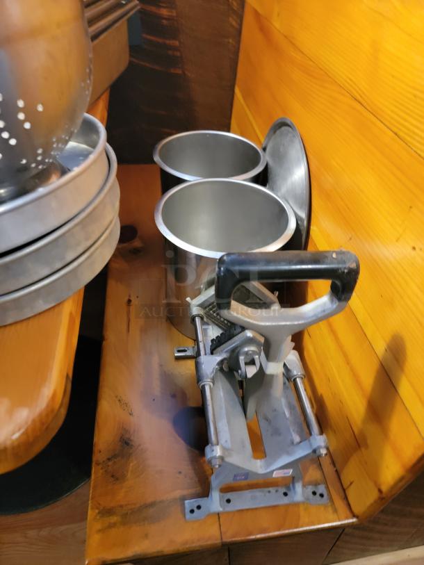 Assorted commercial aluminum cookware including pots and pans with a manual chopper, showing light wear.