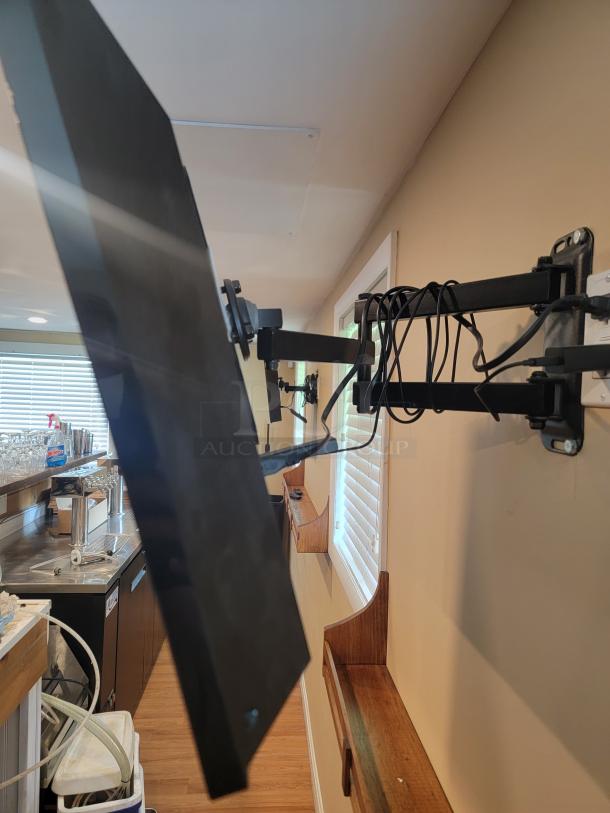 Vizio E280B1 wall-mounted TV with bracket, showing side view. Part of a three-TV auction bundle. Buyer must remove.