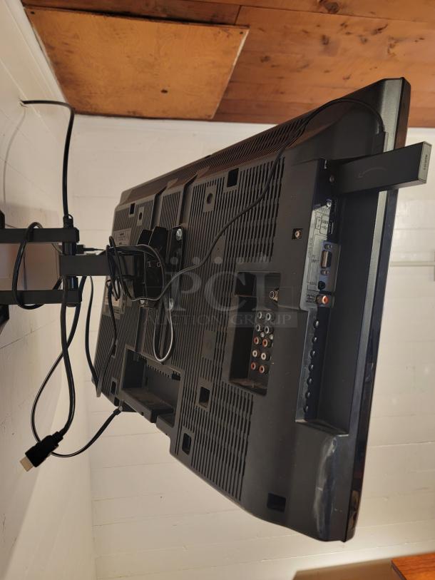 Wall-mounted Vizio E280B1 TV showing rear ports and cables. Includes mounting bracket. Ideal for home or office use.