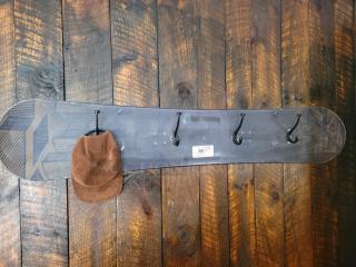 Snowboard wall-mount coat rack with four hooks, black finish, unique design. Includes tag labeled "59". Perfect for winter sports enthusiasts.