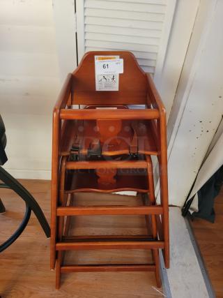 Sturdy wooden restaurant-style high chair with safety straps. Durable, easy to clean, ideal for cafes or home use. Auction label "61".