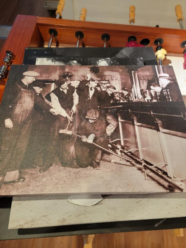 Unique wall art collection featuring black and white historical scene mounted on a wooden frame. Excellent condition, buyer must remove.