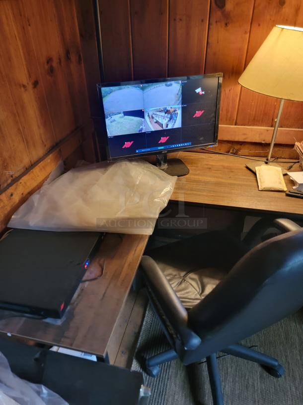 Complete office setup including a desk, monitor showing surveillance feeds, leather office chair, and a lamp. Buyer must remove all items.