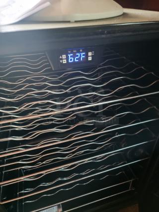 Wine cooler with digital temperature display reading 62°F. Features multiple wire shelves in good condition.