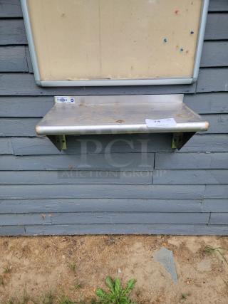 Profeeshaw stainless steel shelf with visible wear. Sturdy, easy-to-clean surface ideal for diverse spaces. Includes manufacturer label.