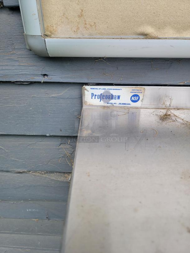 Profeeshaw stainless steel shelf with visible label indicating model PR-WMS1224 and NSF certification. Slightly worn condition.