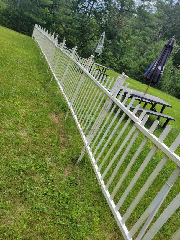 10 white vinyl picket fence sections, 4'x8' each, in a grassy yard. Low-maintenance, classic design, ideal for gardens. Buyer removes.