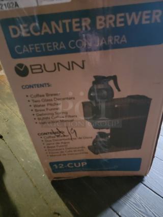 Brand new Bunn 12-Cup Decanter Brewer in box; commercial-grade coffee machine with two glass decanters and essentials.