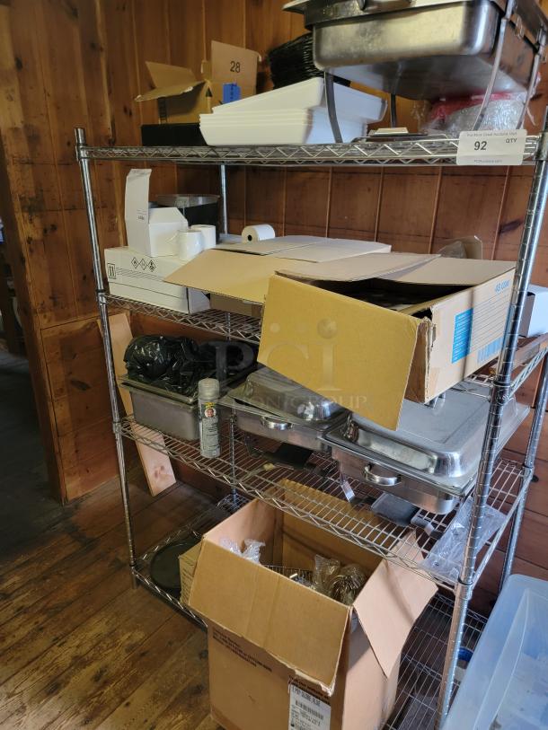 Alt text: "Commercial kitchen supply lot on metal shelves, featuring chafing dishes, paper rolls, and cardboard boxes. Ideal for restaurant use."