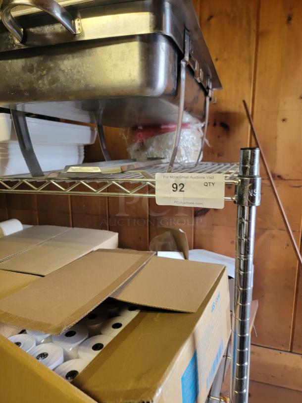 Commercial kitchen supply lot featuring chafing dishes, fry cutter, paper rolls, and more on metal shelving. Auction tag marked "92".