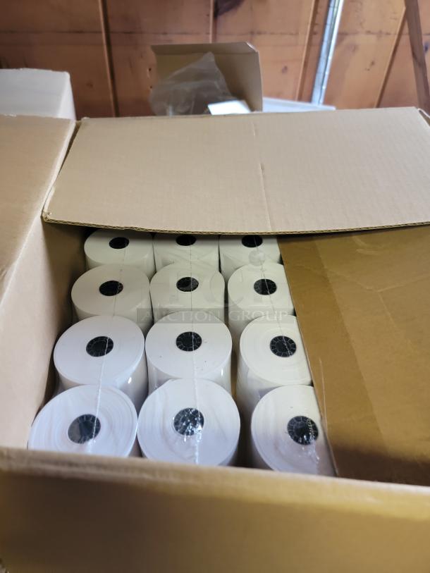 Open box filled with white paper rolls, suitable for restaurant or cafe use, part of a massive kitchen supply lot.
