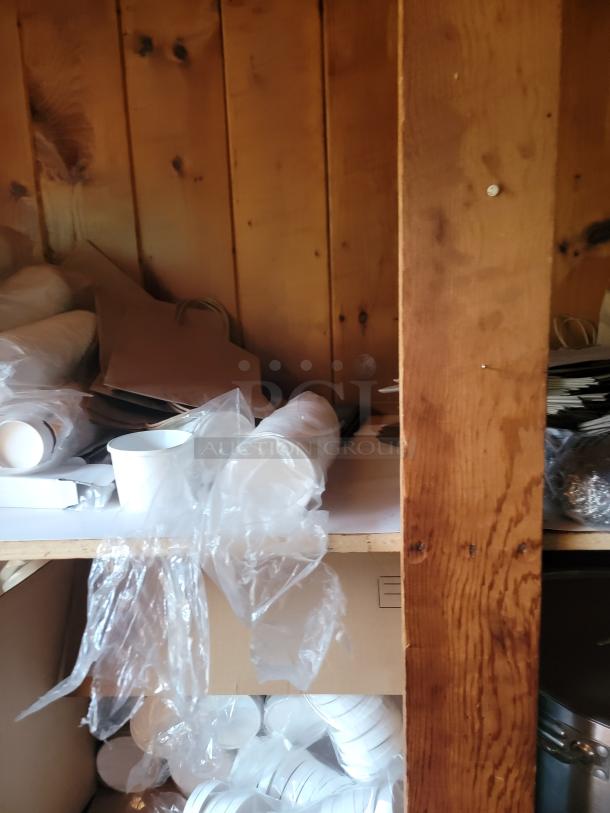 Commercial kitchen and disposable supply lot with to-go containers, cups, bags, and bulk cookware on shelves. Ideal for restaurants.