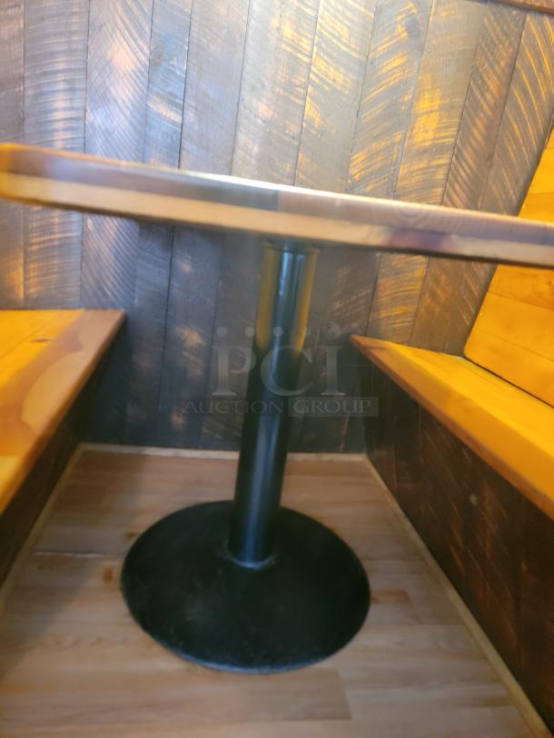 Rustic wooden restaurant booth and table set with black pedestal base. Cozy design with warm wood tones, ideal for dining spaces.