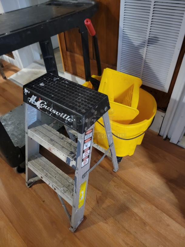 Commercial utility lot with a black rolling cart, yellow mop bucket, and Louisville step ladder. Ideal for business or home use.