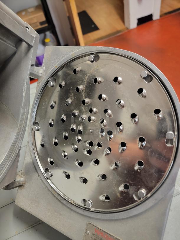 Hobart commercial mixer grater/shredder attachment in used condition, featuring a metal disc with grating holes.