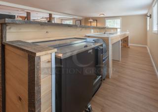 18-foot custom wooden bar with rustic finish, features a sink and under-counter space. Ideal for events or hospitality use.