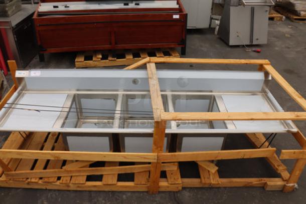 Regency 600S3182424 stainless steel three-compartment commercial sink with two drainboards. Minor scratches and dents.