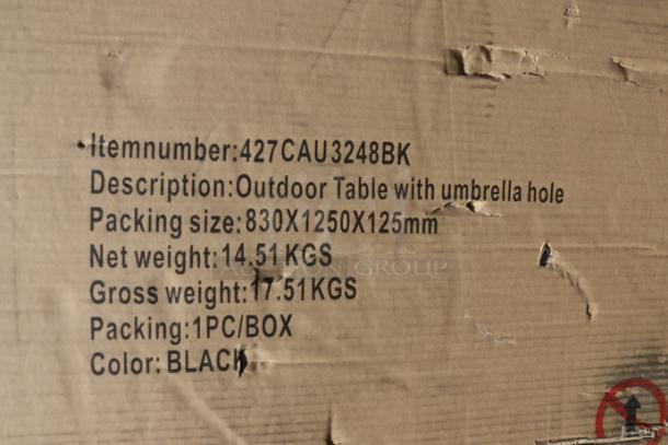 Damaged packaging of Lancaster Table & Seating 427CAU3232BK black outdoor table with umbrella hole, specs visible.