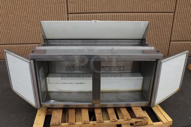 Avantco APT-60-HC 60" 2-door refrigerated sandwich prep table with open doors, showing interior shelves, on a pallet.