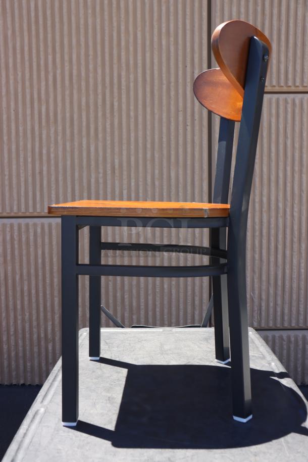 Brand new Lancaster Table & Seating boomerang style metal chair with wood seat, out of original packaging, side view.