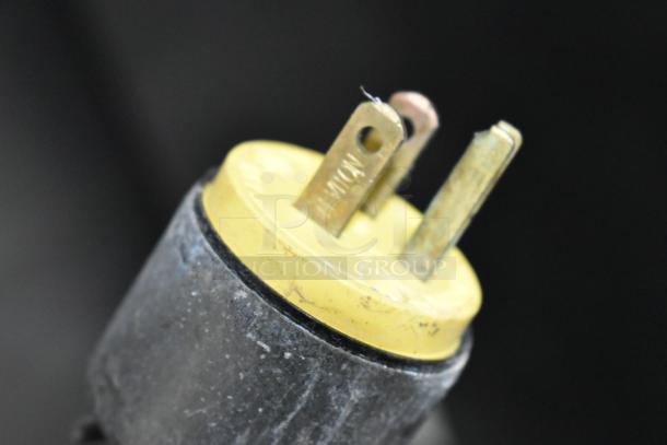 Close-up of a three-prong plug for the Alto Shaam 1000-UP Heated Holding Cabinet, showing a yellow base and metal prongs.
