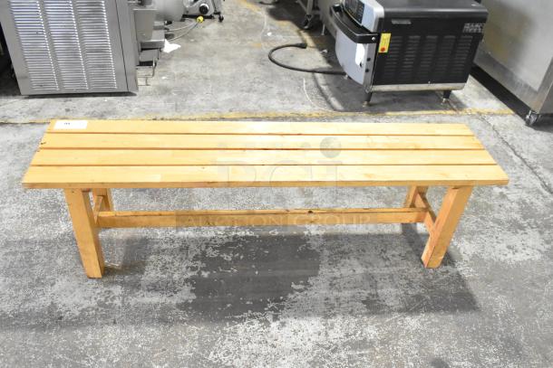 Wooden bench with slatted seat, light finish, sturdy frame. Minor wear visible, tagged with number 99. Suitable for indoor use.