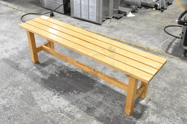 Wooden bench with a natural finish, featuring a slatted top and sturdy legs. Shows mild wear, ideal for indoor use.