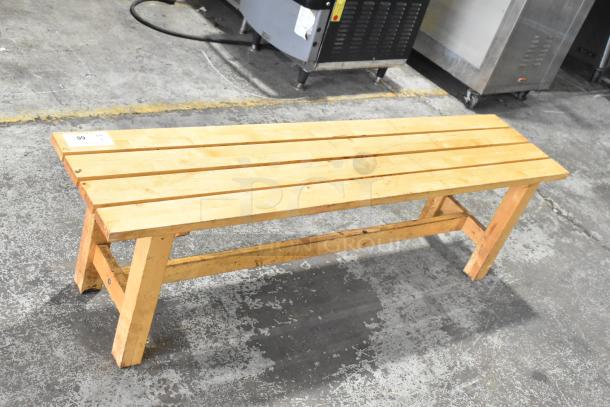 Wooden bench with slatted seat, natural finish, sturdy condition, auction tag number 99 attached.