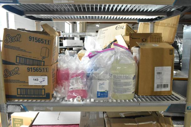 Auction lot of Scott soap dispenser refills, pink lotion skin cleanser, foam skin cleaner on metal shelf; various boxes visible.