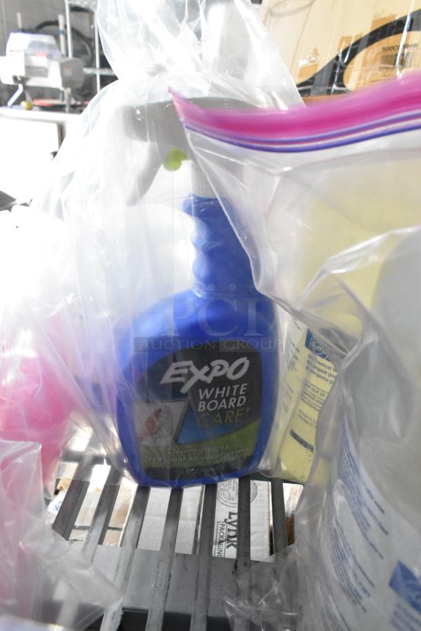 Tiered lot of various cleaning items, including Expo White Board Care spray. Wrapped in clear plastic packaging.